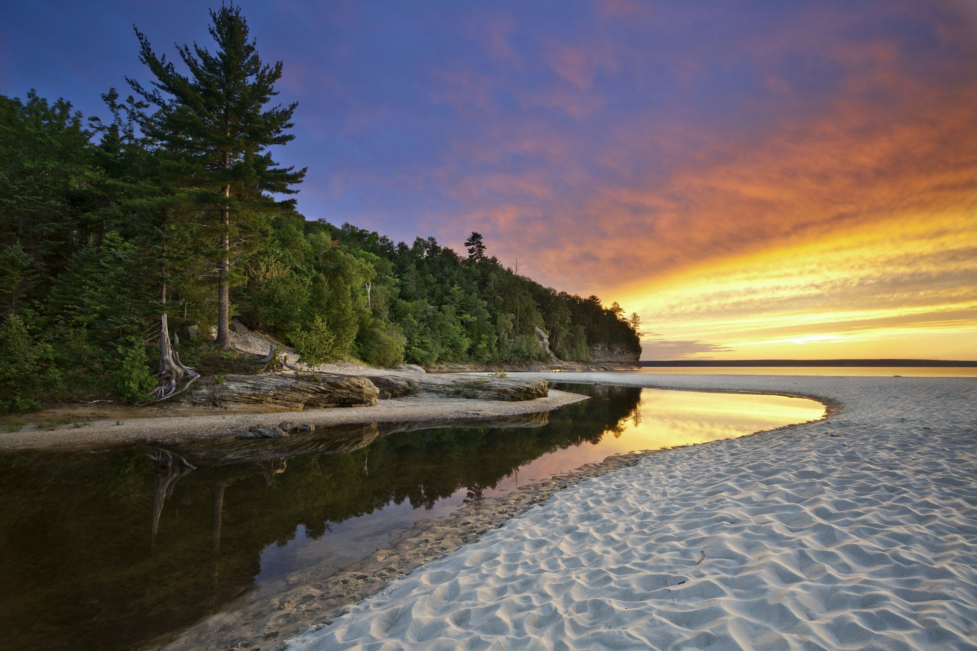 The forest meets the sand during sunset at Miners Beach at Pictured Rocks National Lakeshore.