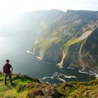 A male hiker looks over the cliffs of Slieve League, which is one of the most popular stops on the Wild Atlantic Way route.