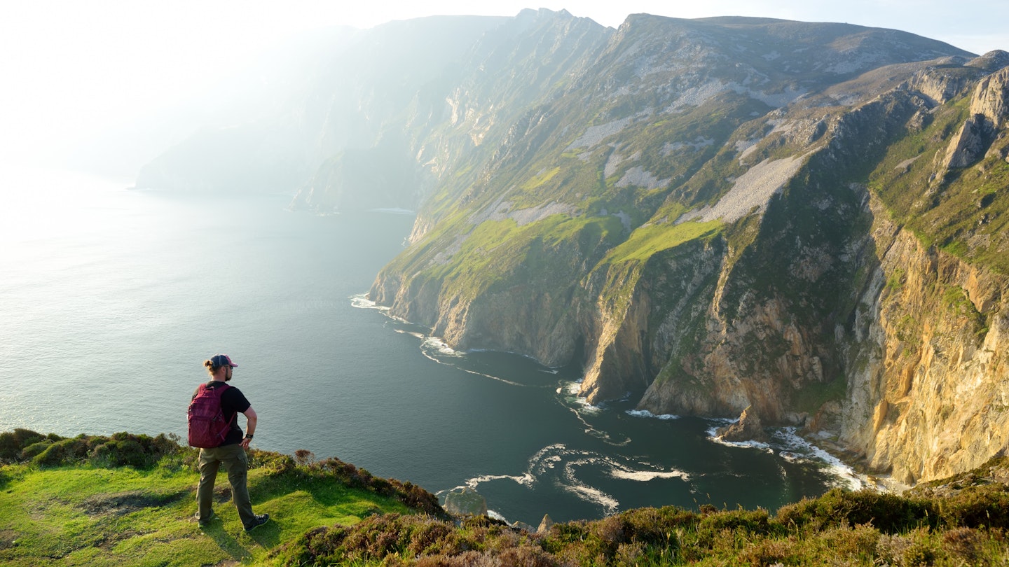 A male hiker looks over the cliffs of Slieve League, which is one of the most popular stops on the Wild Atlantic Way route.