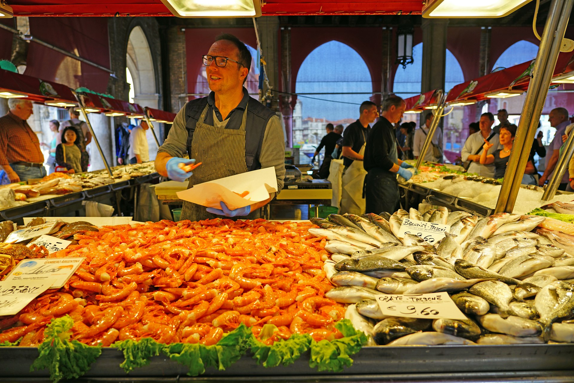 A man selling fresh seafood for sale at the Rialto farmers market (Mercato di Rialto) in Venice, near the Rialto Bridge and the Grand Canal.