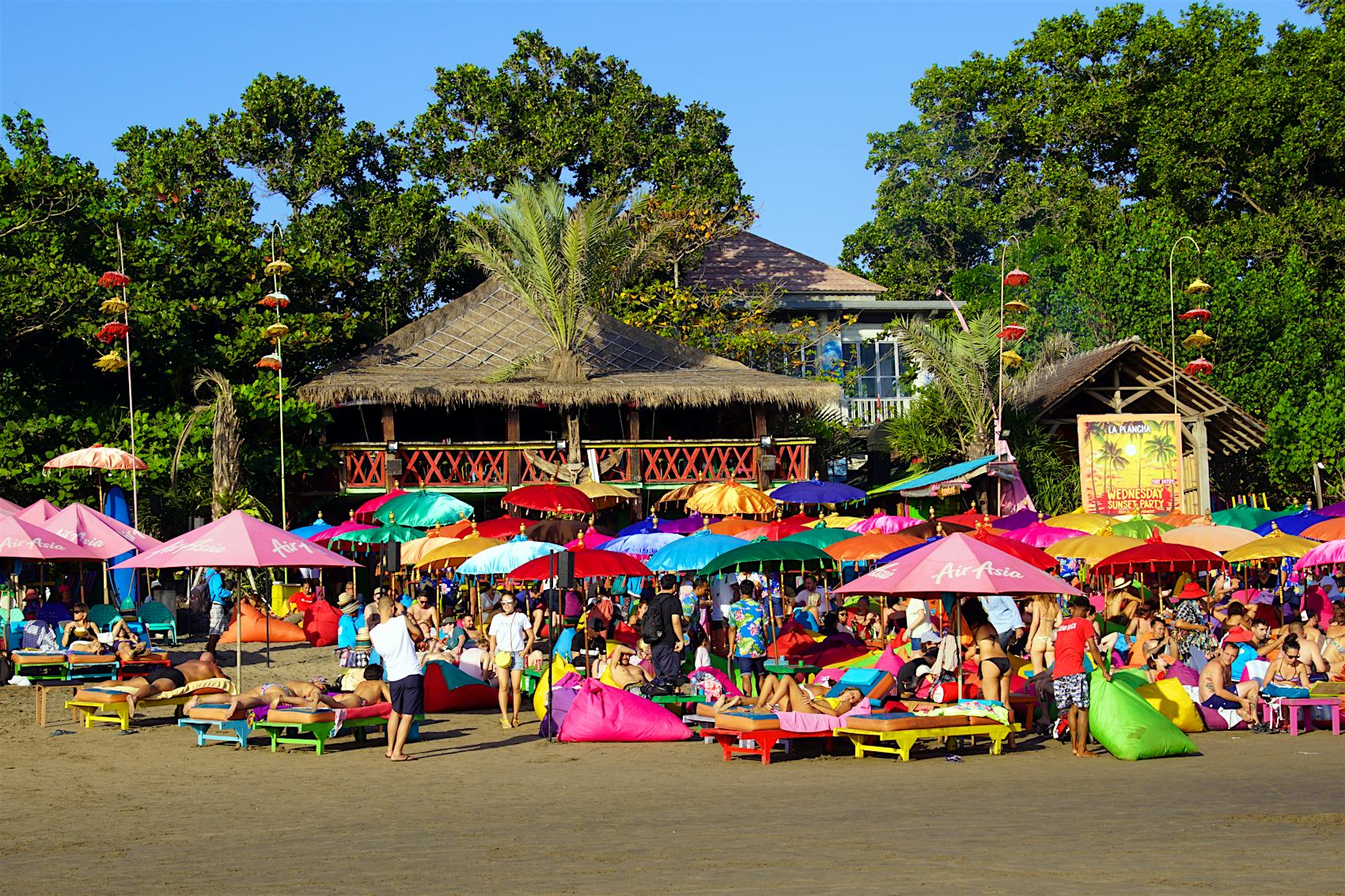 August 14, 2018: A crowd of people under colourful umbrellas outside La Plancha Beach Bar & Restaurant.