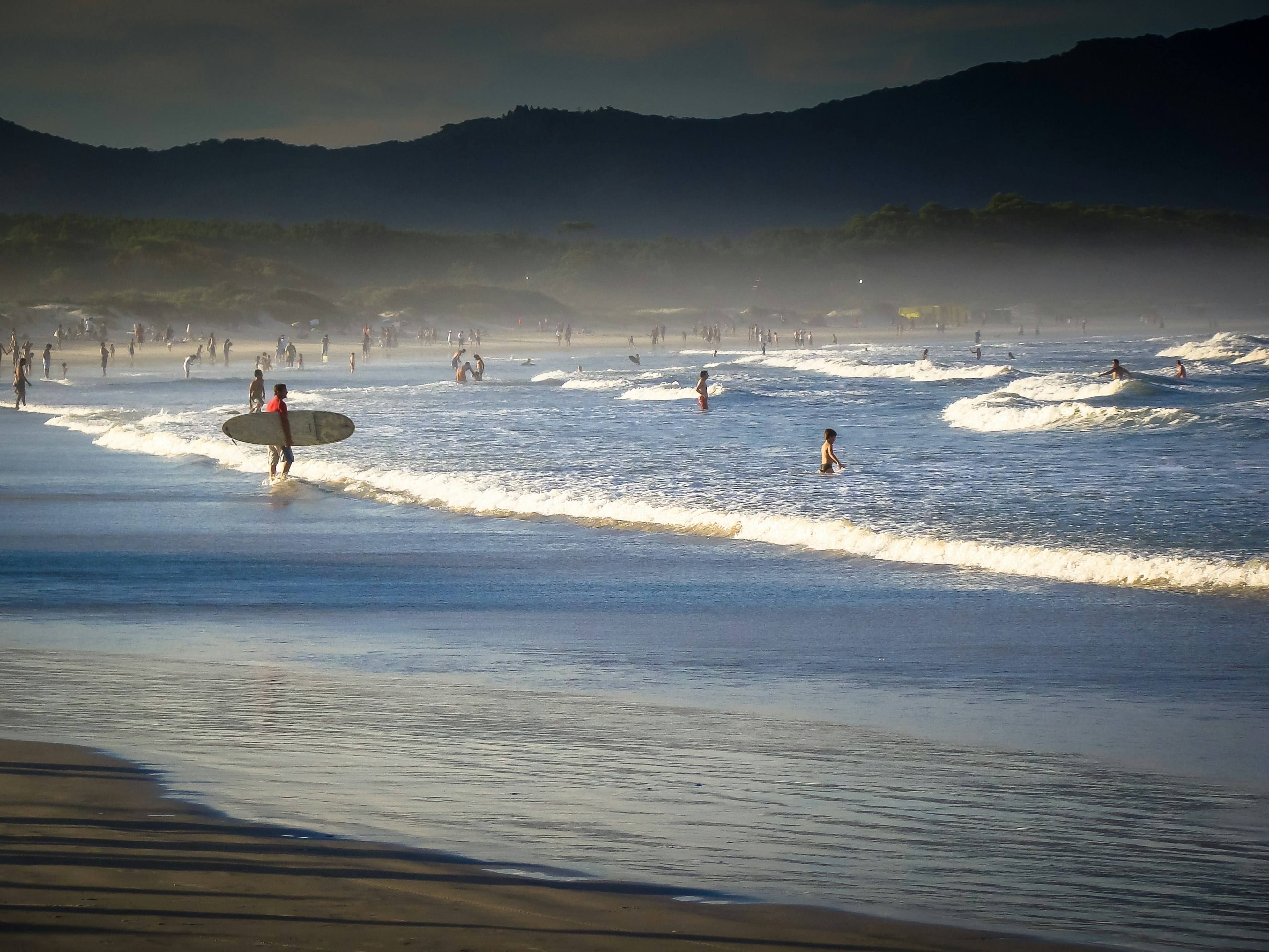 Surfers and swimmers at Barra da Lagoa beach in the late afternoon in ǰóǱ, Brazil