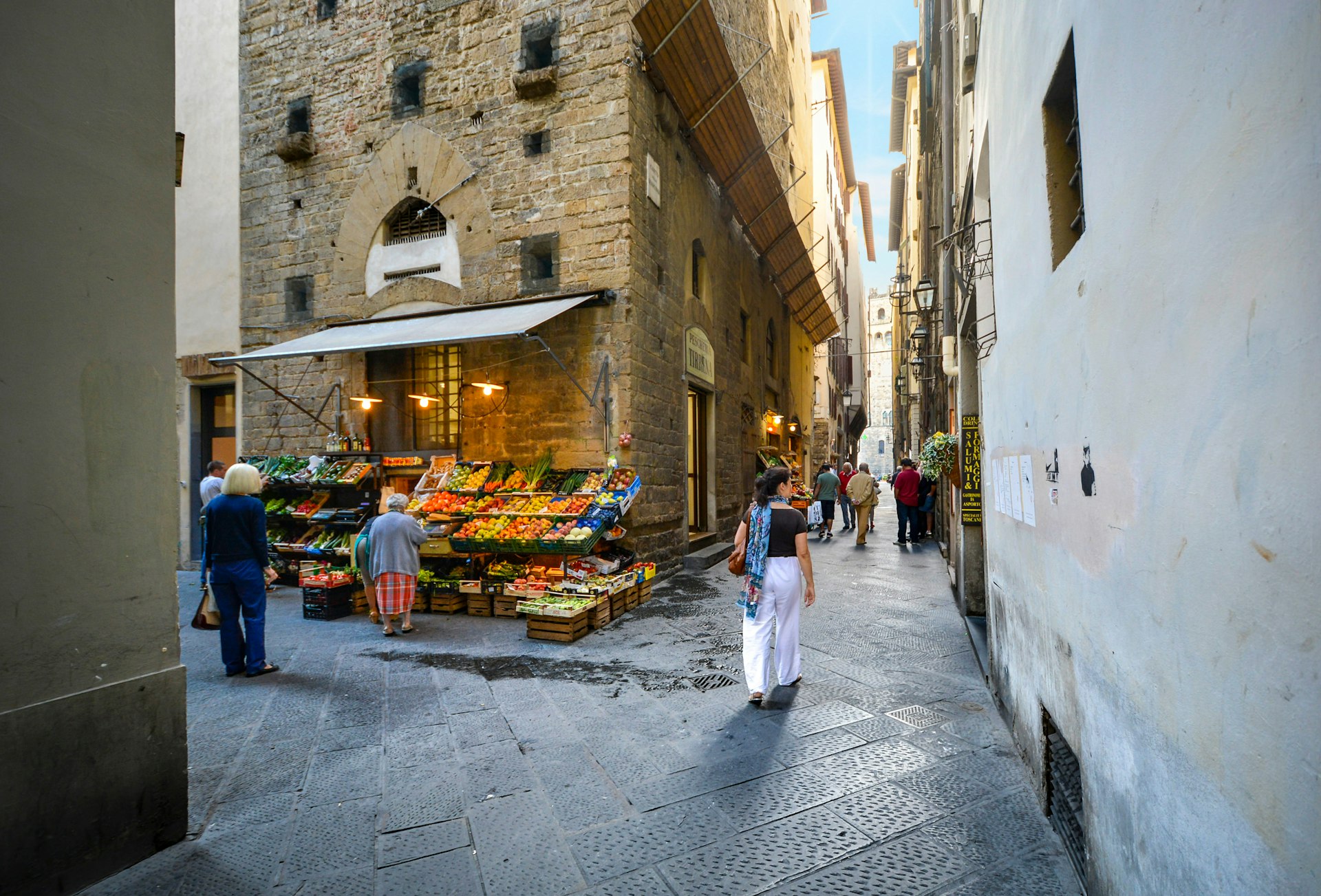 A fresh produce market with some local shoppers in a narrow alley in Florence.