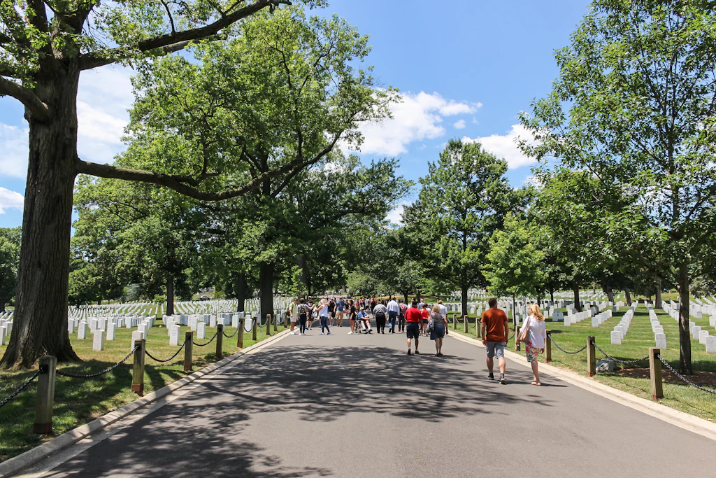 People walk down the paths through the cemetery on a sunny day.