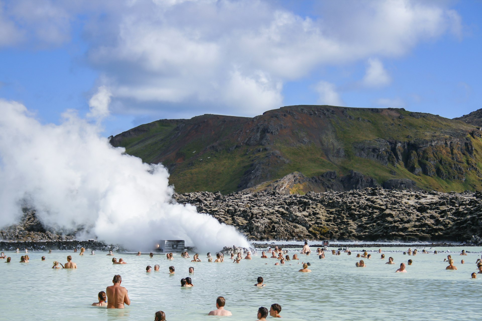 Bathers in a hot spring surrounded by rocky edges