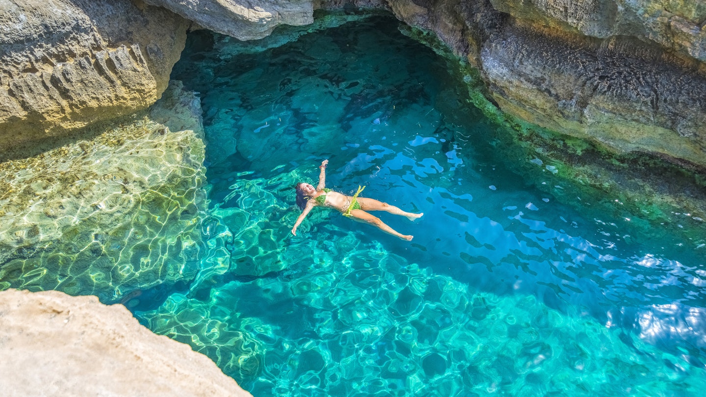 Young woman swimming between the rocks of Preveli beach in Crete.