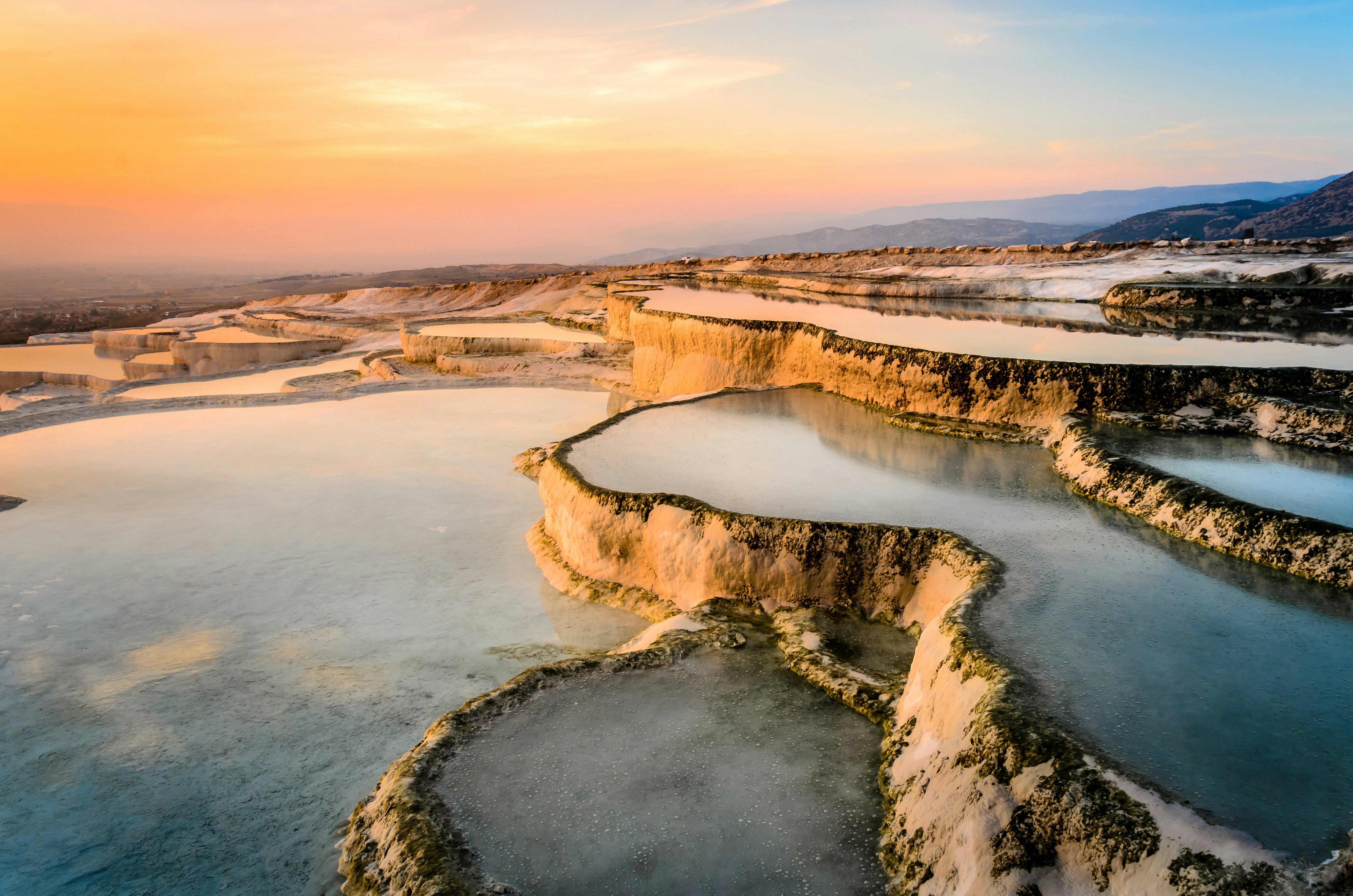 A series of white tiered pools at Pamukkale in the setting sun, Turkey.