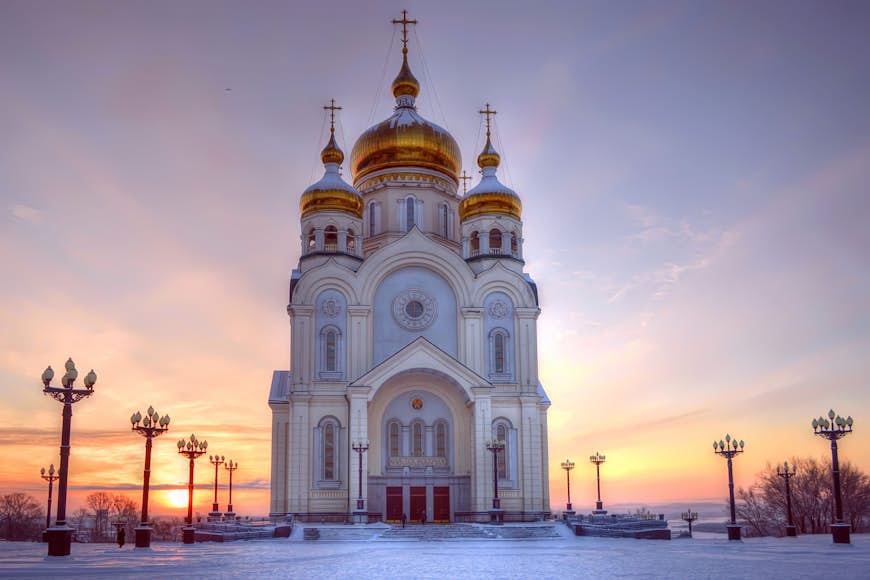 A huge white church with three golden domes on the roof