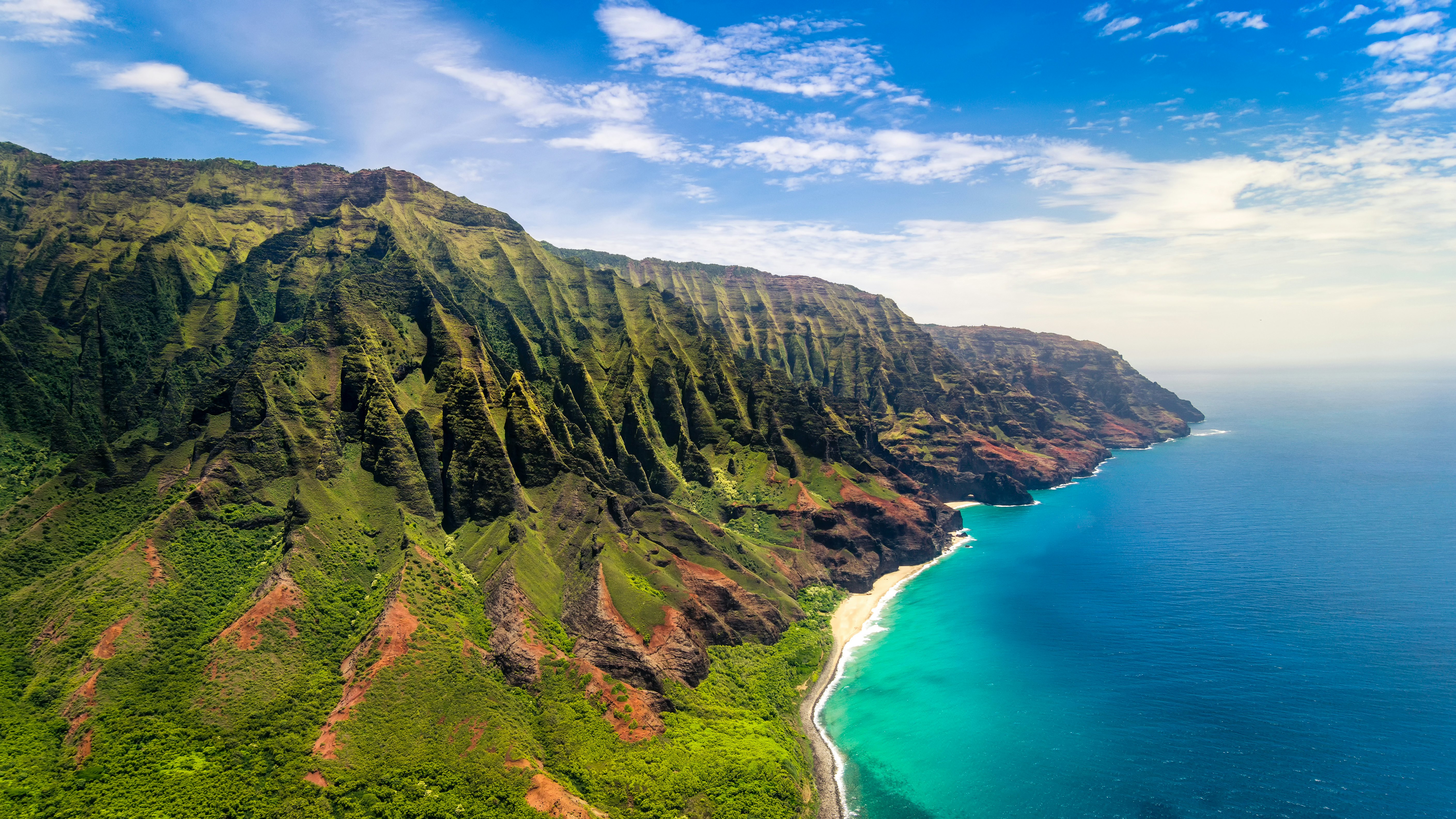 Steep cliffs covered in greenery rise above the sea