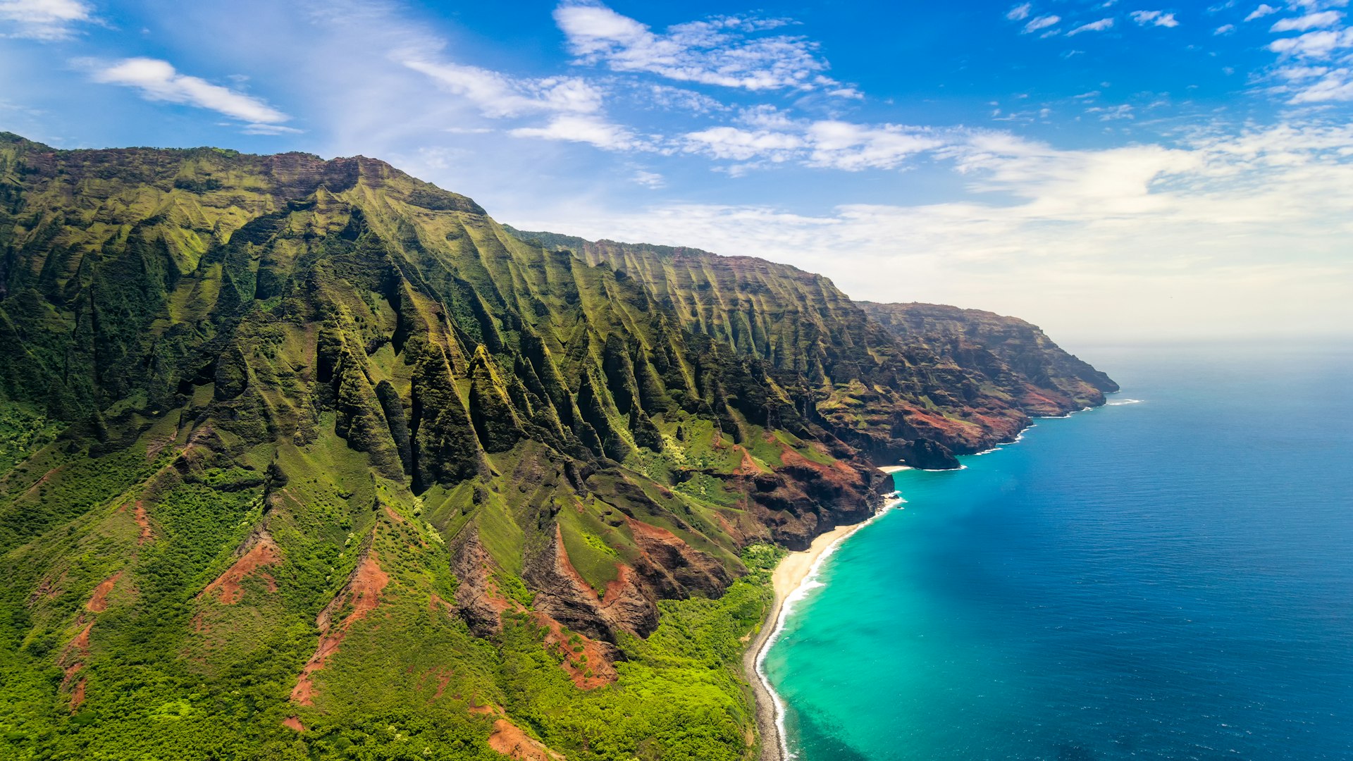 Steep cliffs covered in greenery rise above the sea