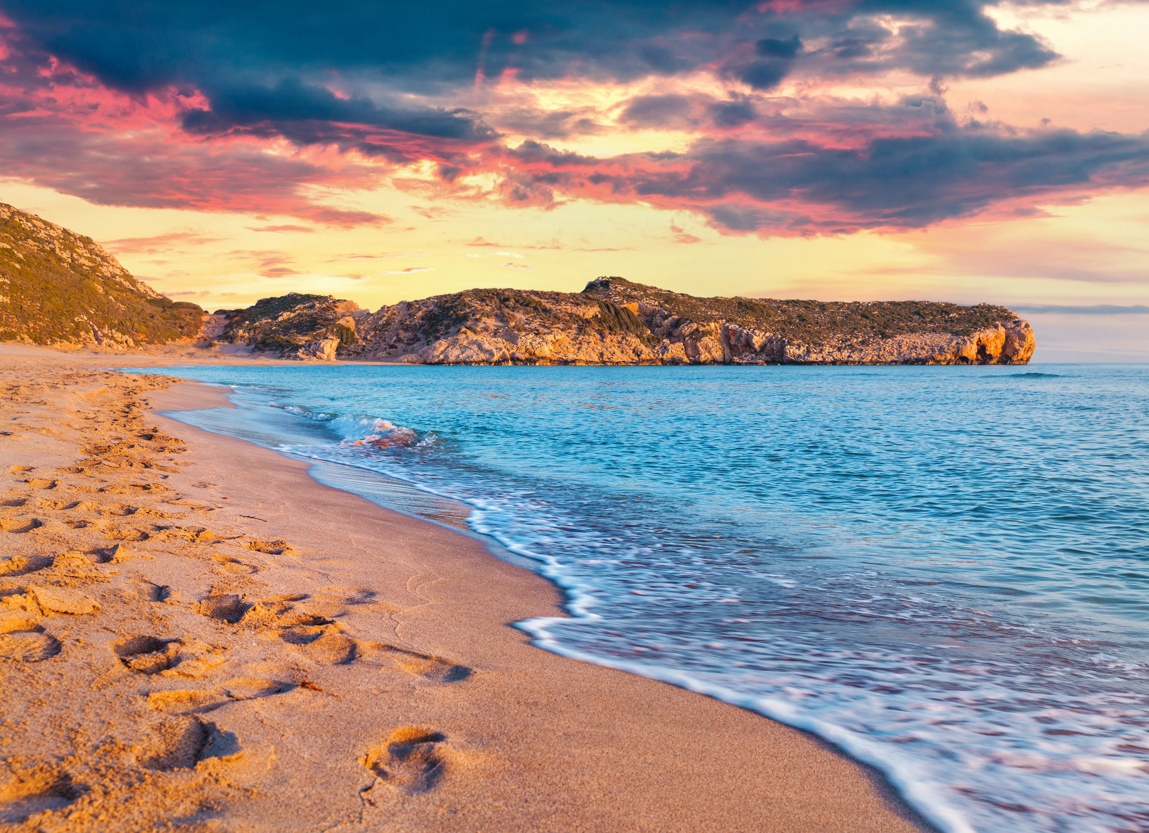 A curved stretch of empty beach as the sun sets