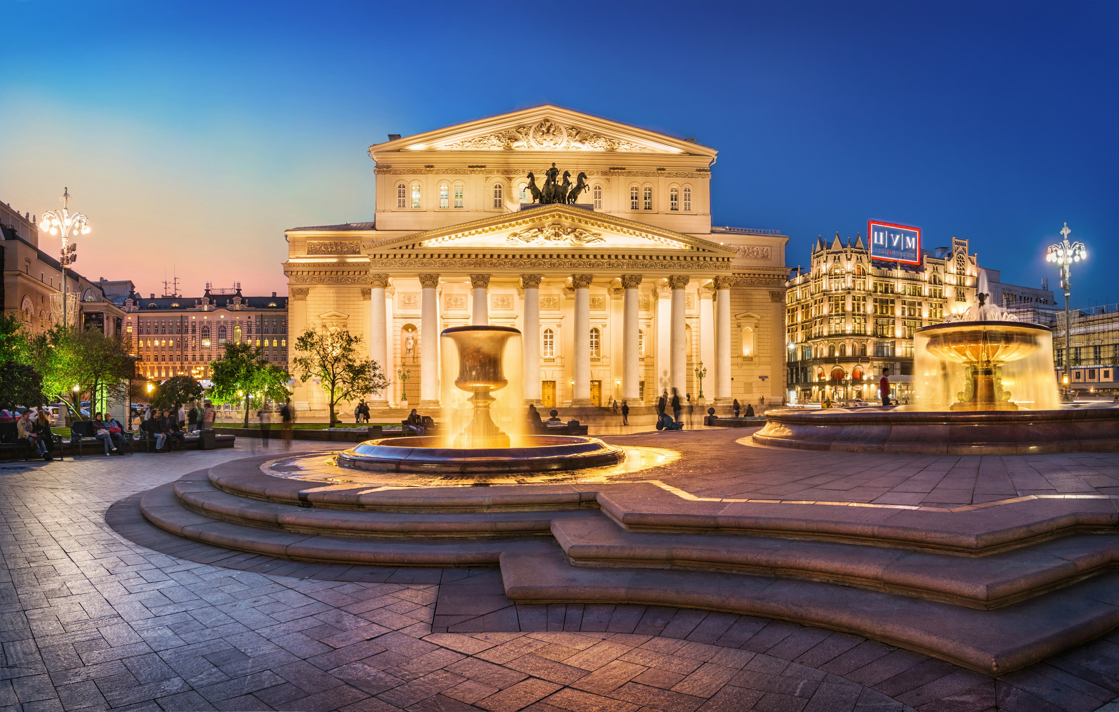 The exterior of a large white building with columns in the evening