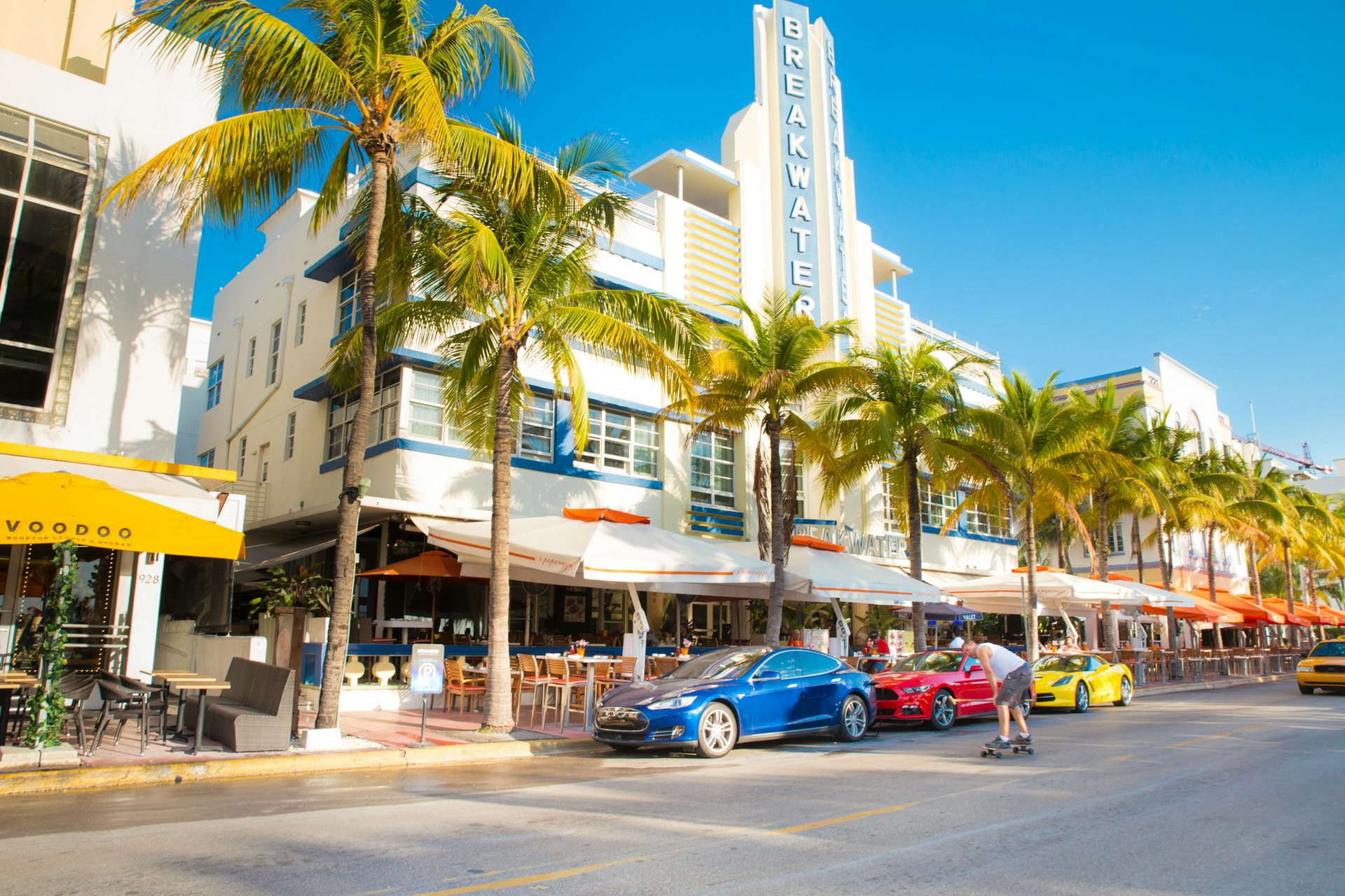 Ocean Drive in the Art Deco district of South Beach, Miami on a sunny day with cars and palm trees