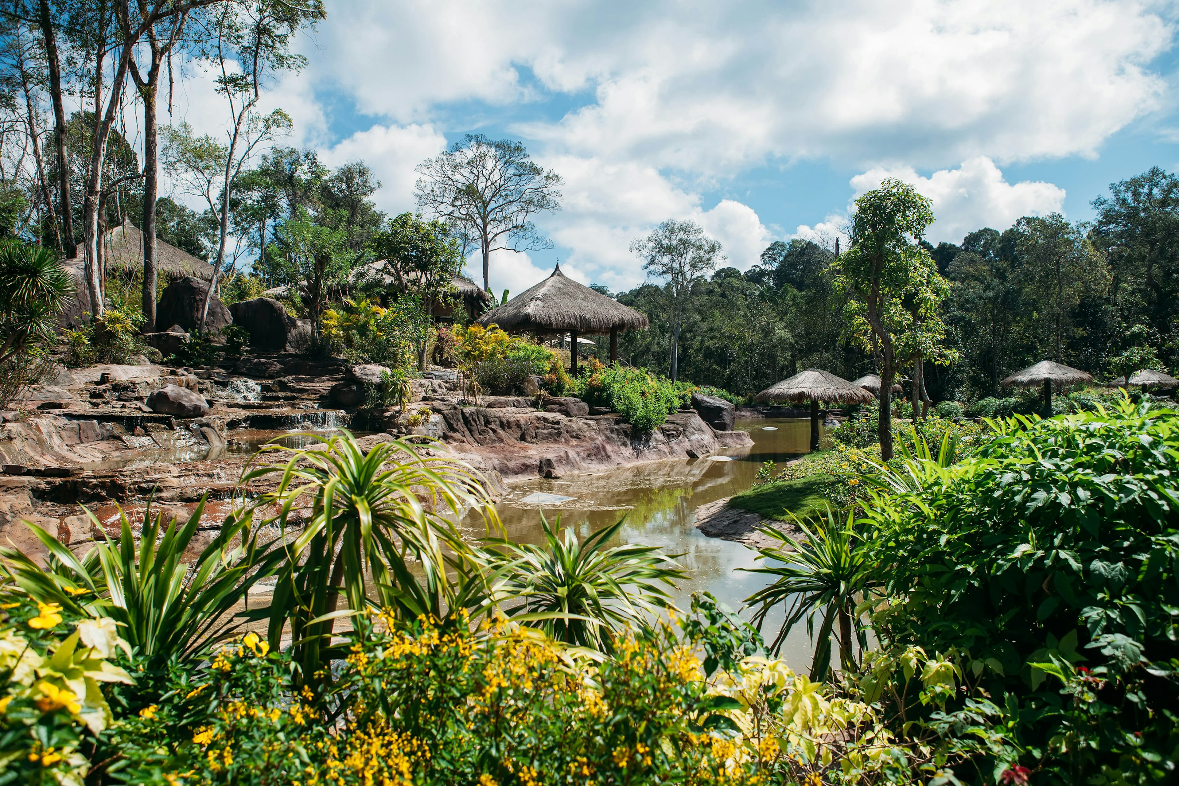 Jungle landscape with flowing water and small huts in Phu Quoc National Park.