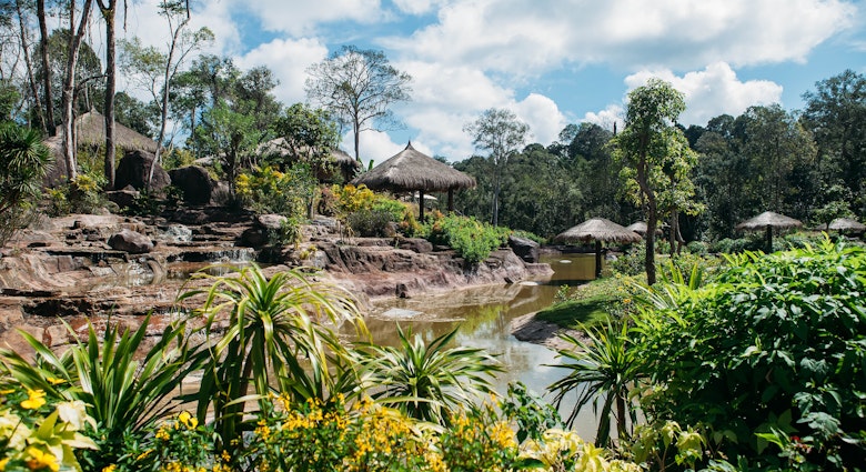 Jungle landscape with flowing water and small huts in Phu Quoc National Park.