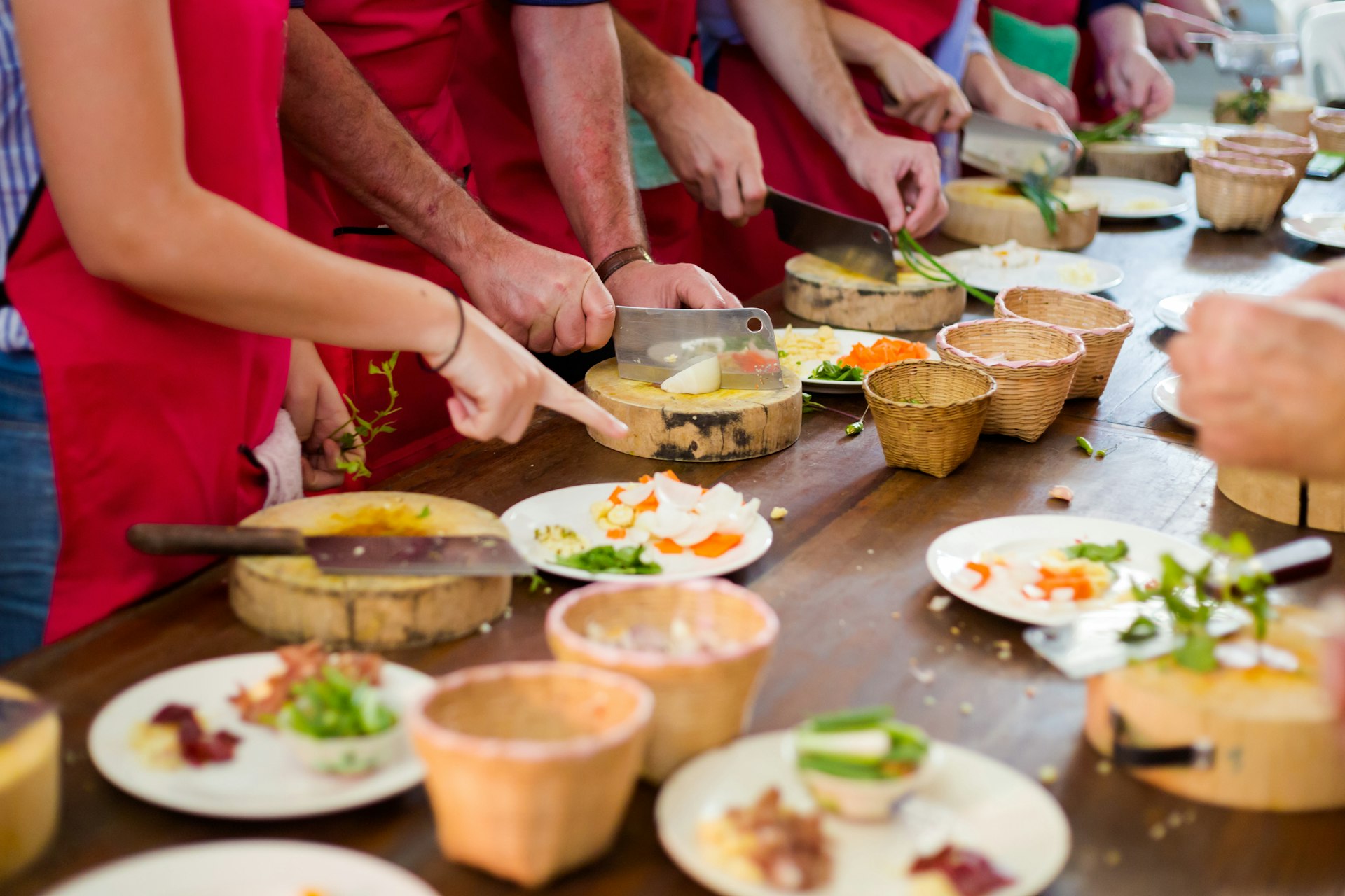 A close-up of hands preparing food at a long table