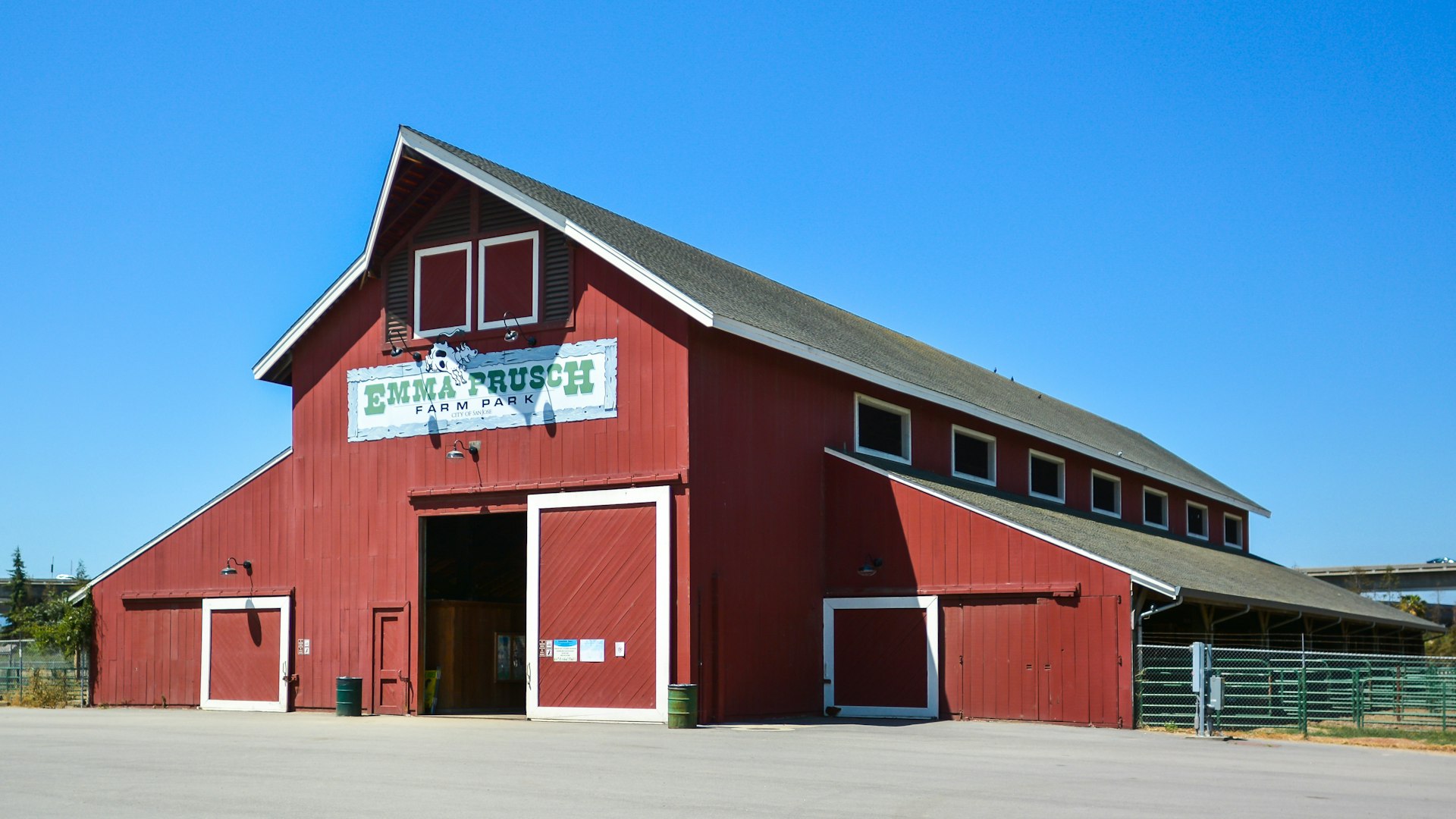 A large red wooden barn building with a sign outside that reads "Emma Prusch Farm Park"