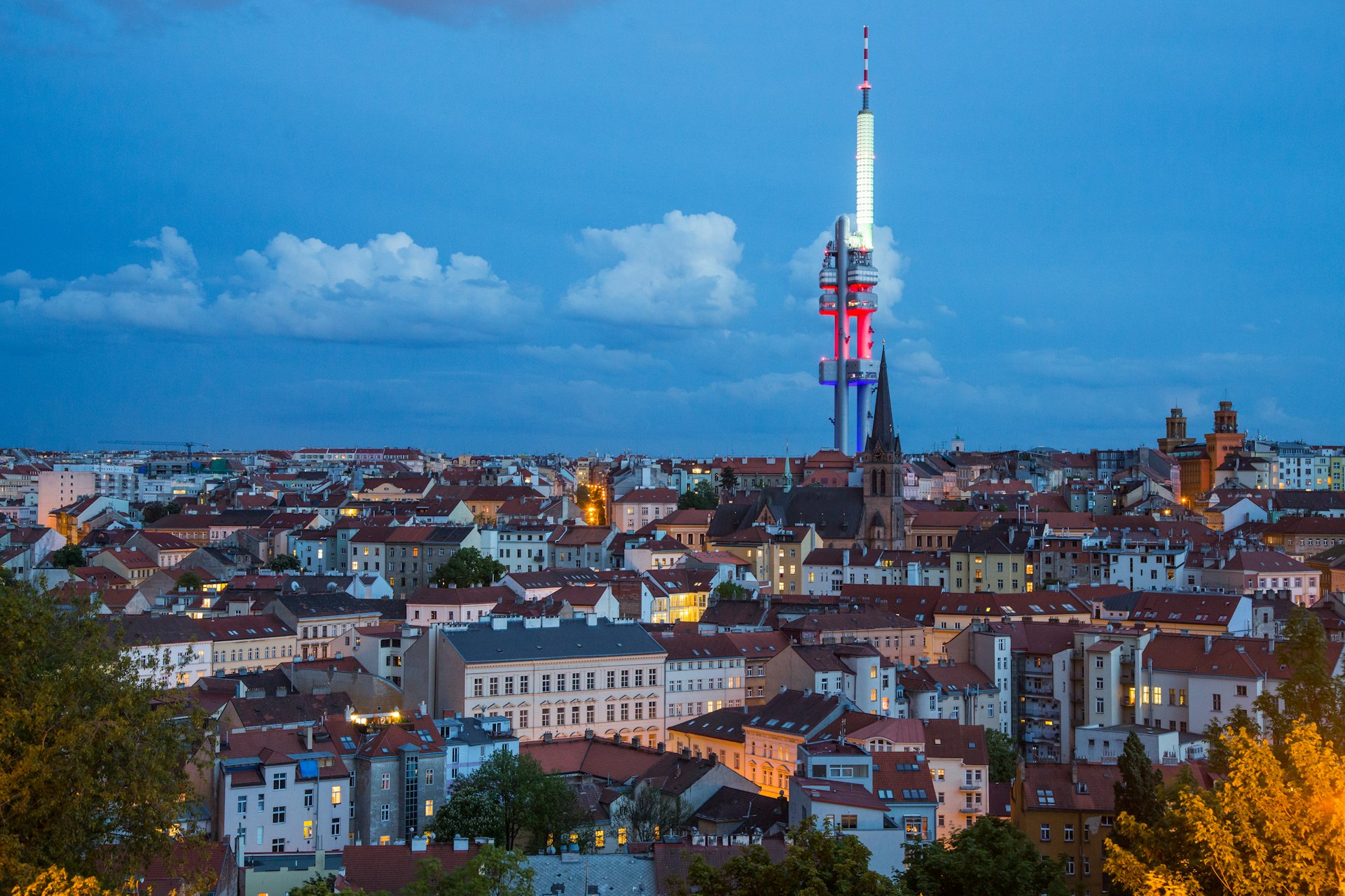 Una gran torre de televisión domina el cielo nocturno en una vista aérea de un área urbana