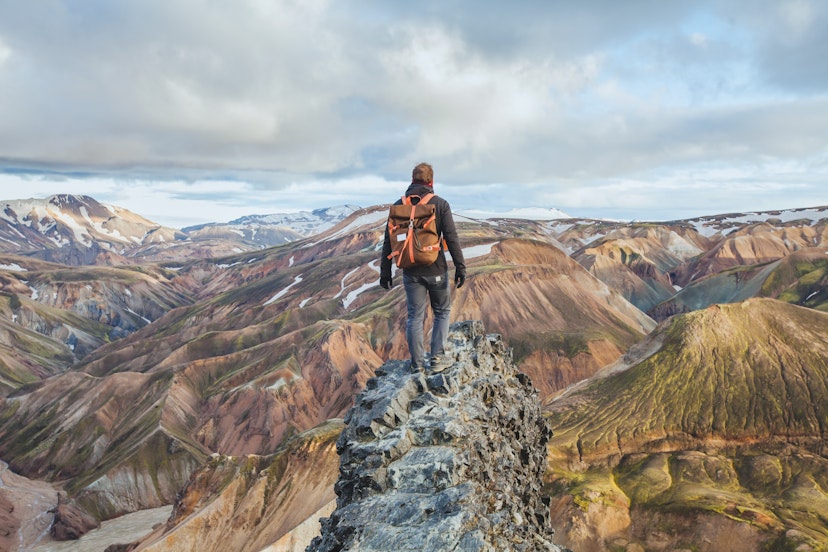 adventure travel, hiking in Iceland with a backpack, tourist looking at the colorful landscape of Landmannalaugar