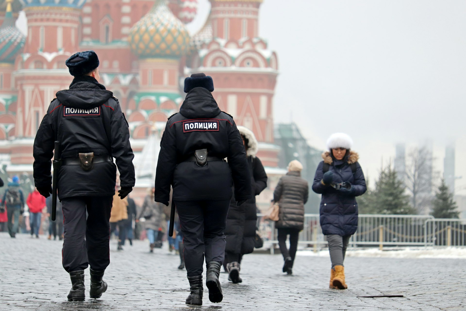 Two police officers dressed in black walk through a heavily touristed area