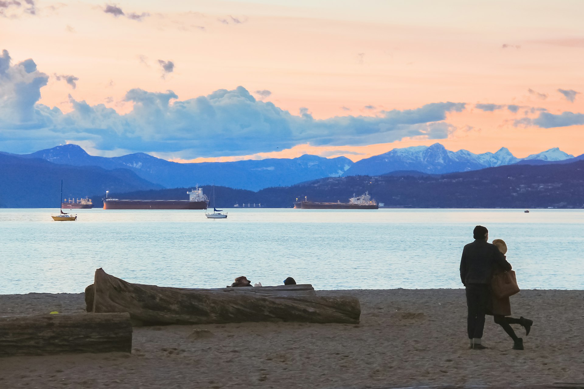 A couple embraces while watching cargo ships in Vancouver's Kitsilano Beach over Burrard Inlet