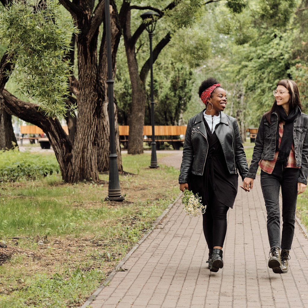 Affectionate lesbian couple in casualwear taking walk in public park at leisure