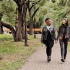 Affectionate lesbian couple in casualwear taking walk in public park at leisure