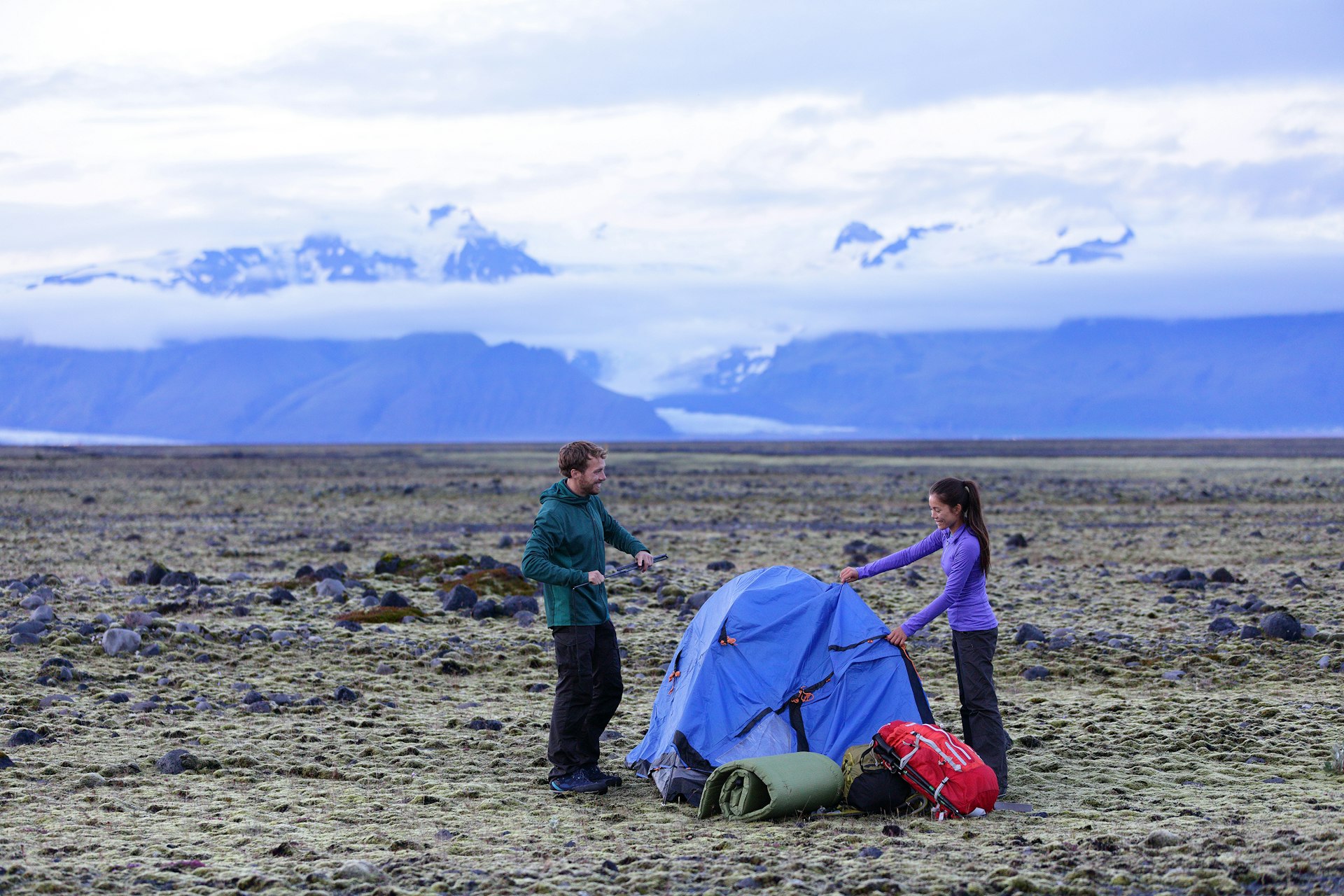 Camping couple pitching tent after hiking in Iceland backcountry