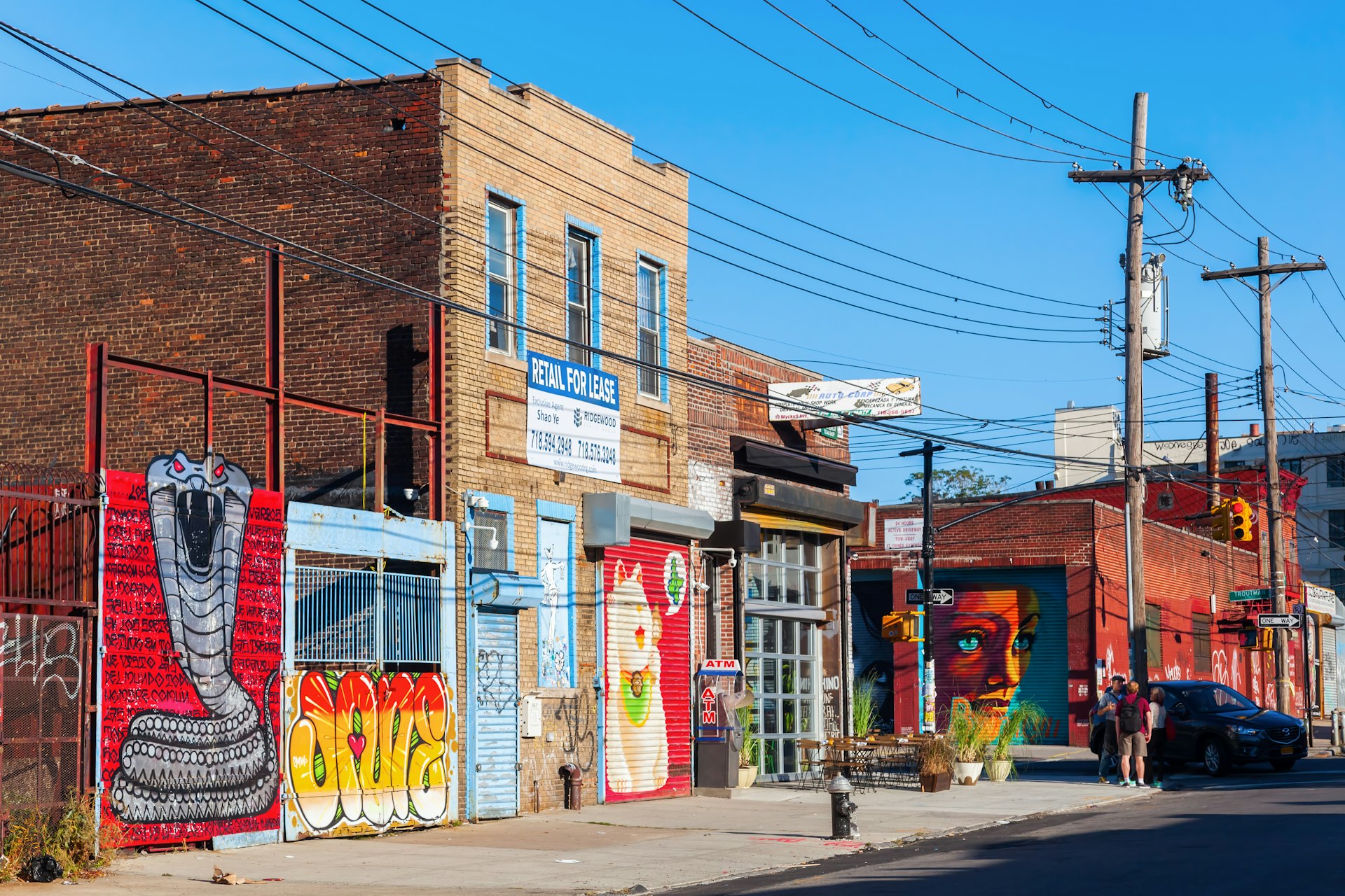 People standing on a corner in Bushwick, Brooklyn, in front of brightly painted mural art