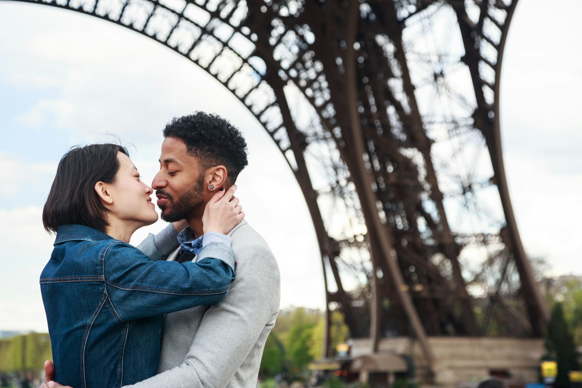 A couple embracing for a kiss under the Eiffel Tower, Paris, France