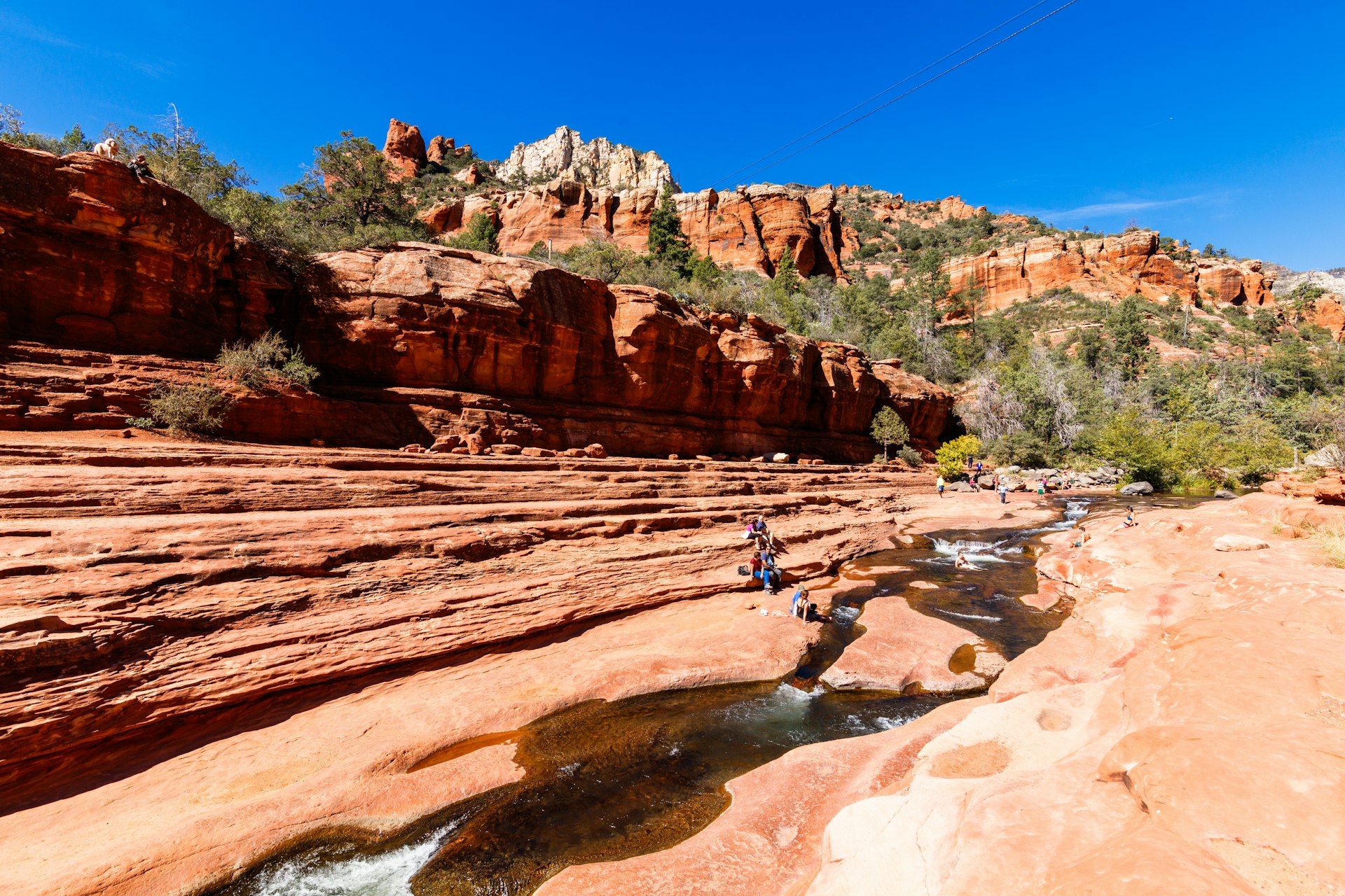 Visitors enjoying a river running through red rock canyons