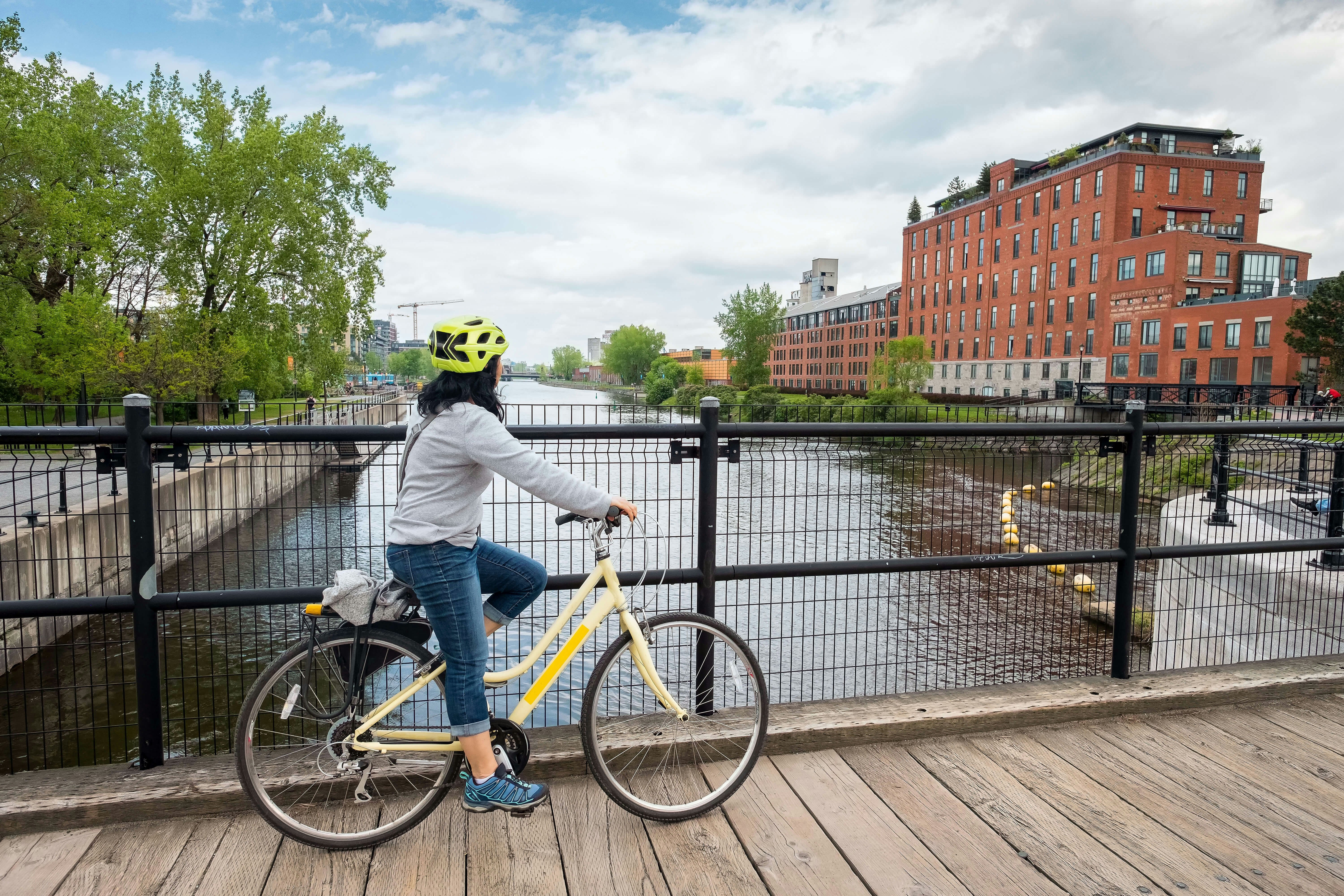A bike rider pauses on a bridge overlooking a canal