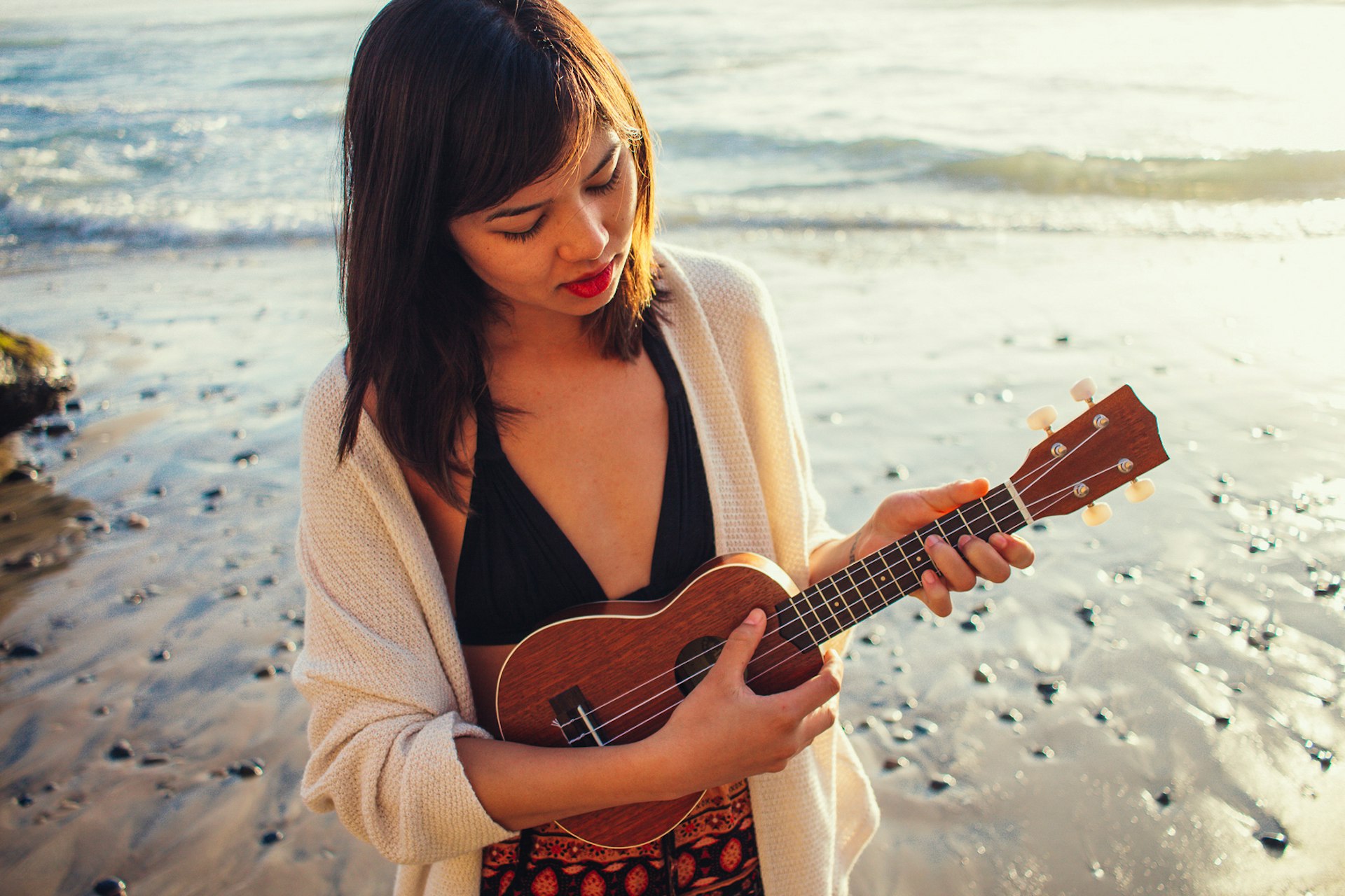 A woman plays the ukulele on the beach in Hawaii