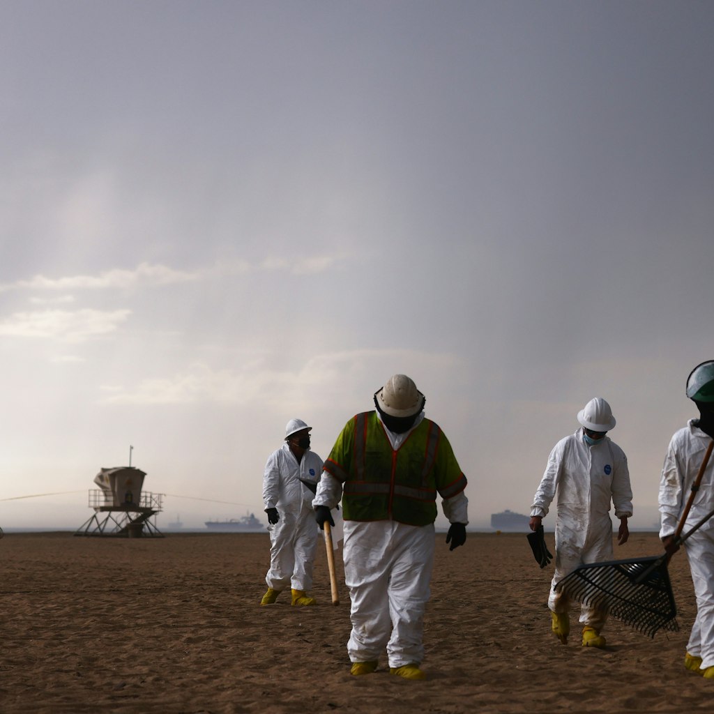 HUNTINGTON BEACH, CALIFORNIA - OCTOBER 04:  Cleanup workers in protective suits depart the closed Huntington State Beach as a storm approaches after a 126,000-gallon oil spill from an offshore oil platform on October 4, 2021 in Huntington Beach, California. The spill forced the closure of the popular Great Pacific Airshow yesterday with authorities closing beaches in the vicinity.  (Photo by Mario Tama/Getty Images)