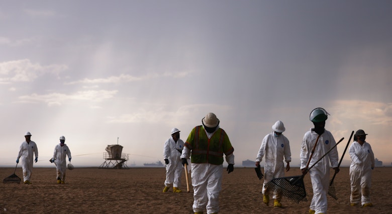 HUNTINGTON BEACH, CALIFORNIA - OCTOBER 04:  Cleanup workers in protective suits depart the closed Huntington State Beach as a storm approaches after a 126,000-gallon oil spill from an offshore oil platform on October 4, 2021 in Huntington Beach, California. The spill forced the closure of the popular Great Pacific Airshow yesterday with authorities closing beaches in the vicinity.  (Photo by Mario Tama/Getty Images)
