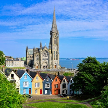 Colorful row houses with towering cathedral in background in the port town of Cobh, County Cork.