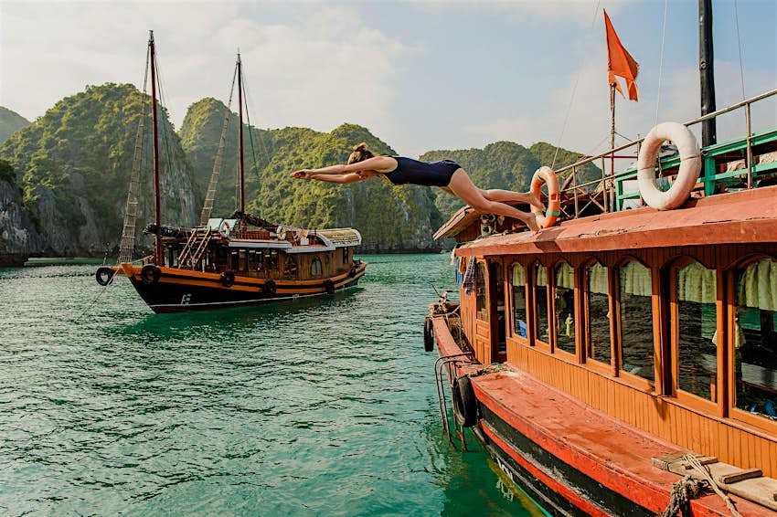 Woman diving off of a boat in Halong Bay Vietnam