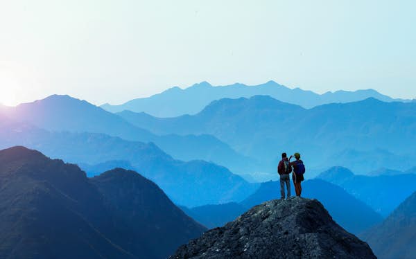 two people standing on mountain taking picture