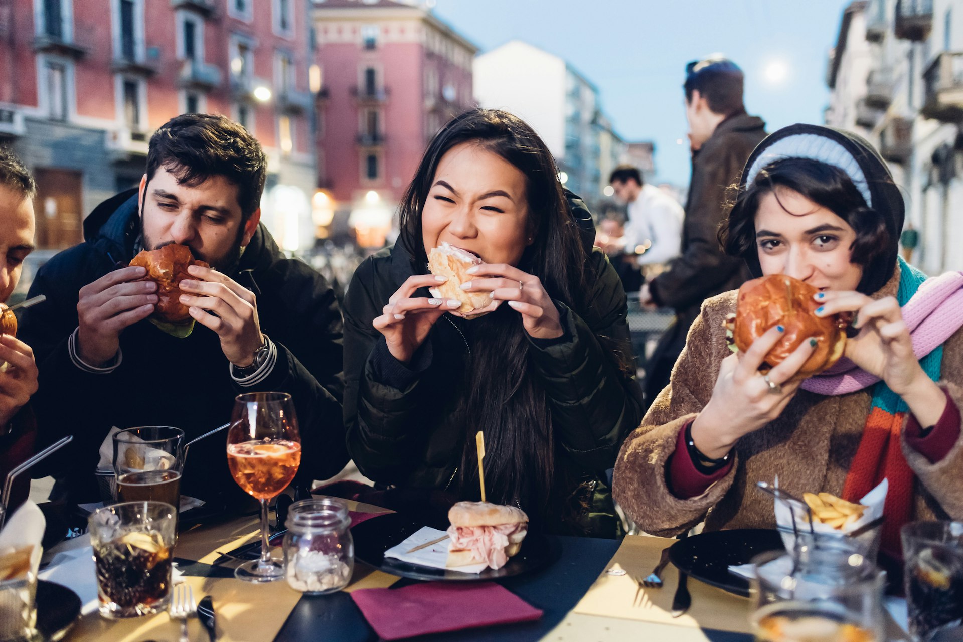 Friends enjoying burgers and drinks at an outdoor cafe in Milan