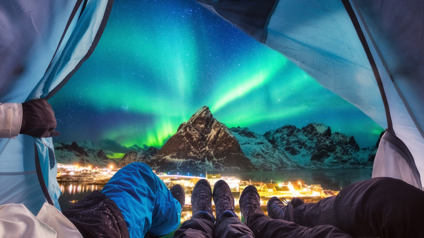 Group of climber are inside camping with aurora borealis over mountain at Sakrisoy village