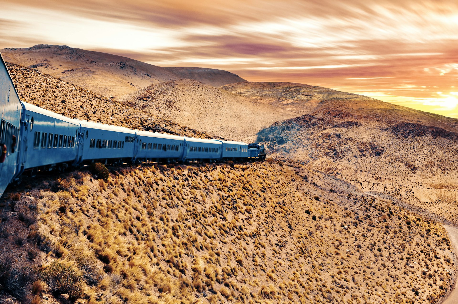 A train crosses a desert-like landscape in Salta at Sunset