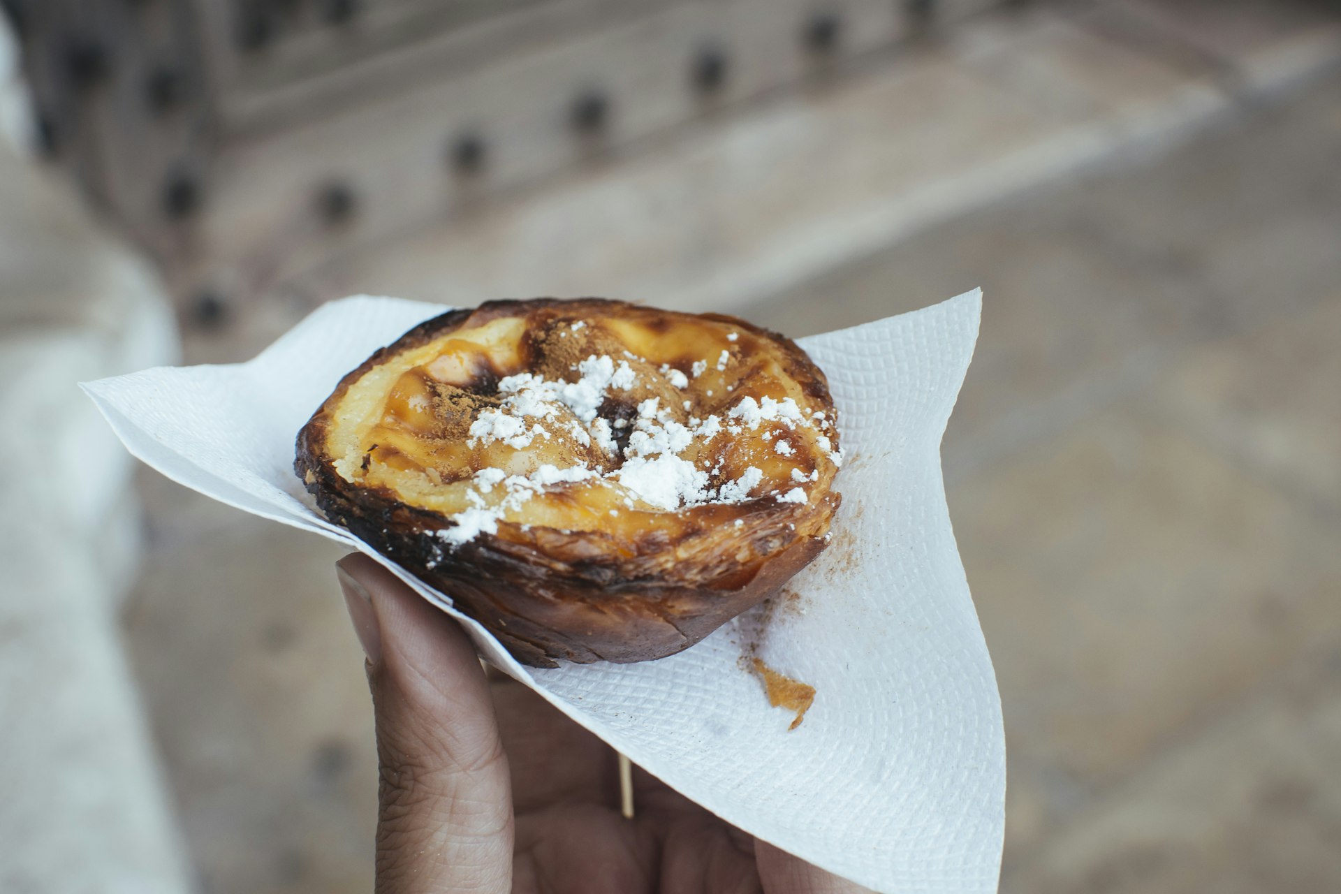 Hand holding a traditional Portuguese tart from Pasteis de Belem in Lisbon, Portugal