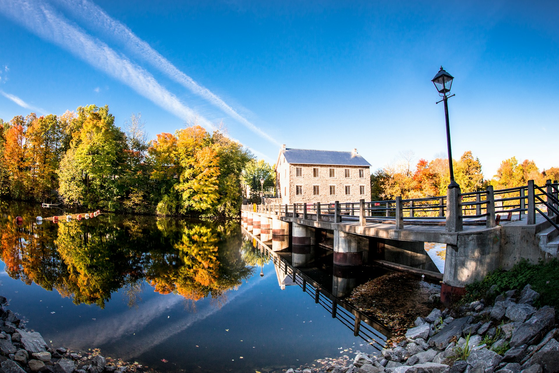 Old mill and autumn trees reflected in still river