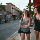 Two women laugh together while walking down a street in Key West
