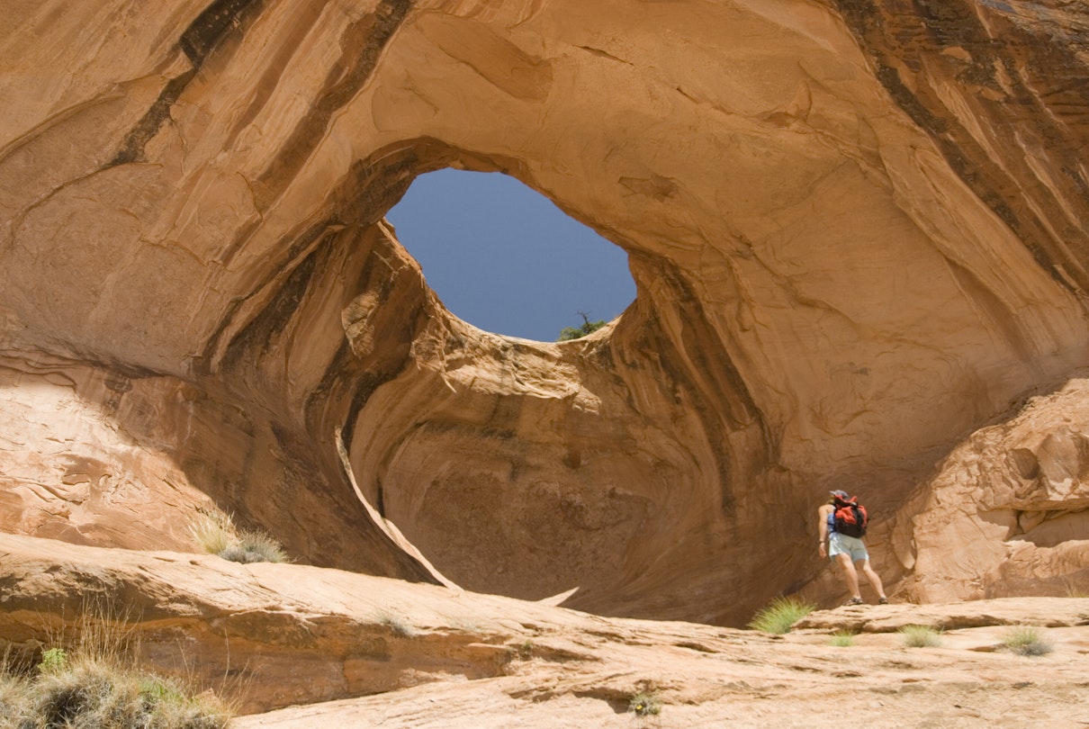 A hiker looks at Bowtie Arch outside of Moab, Utah.