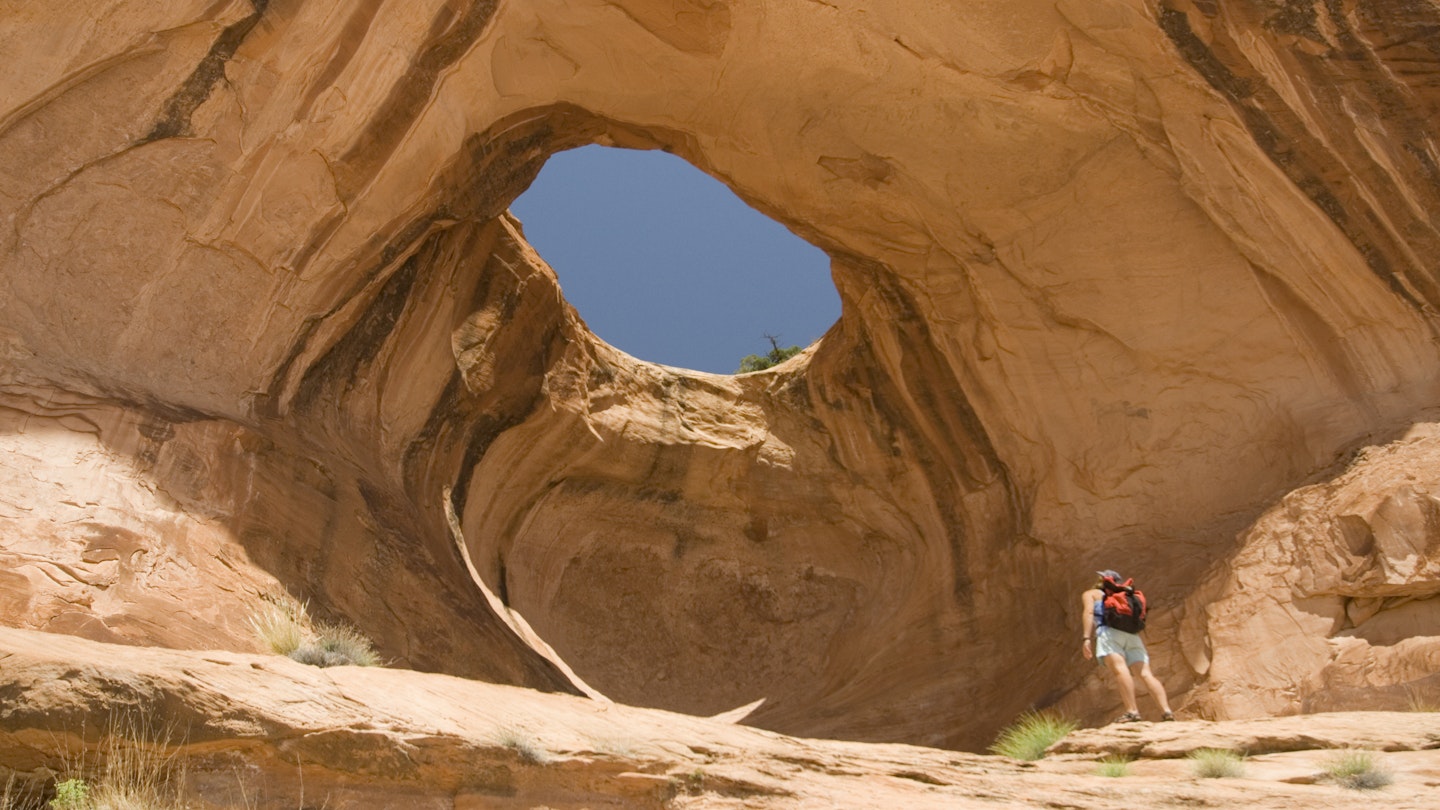A hiker looks at Bowtie Arch outside of Moab, Utah.