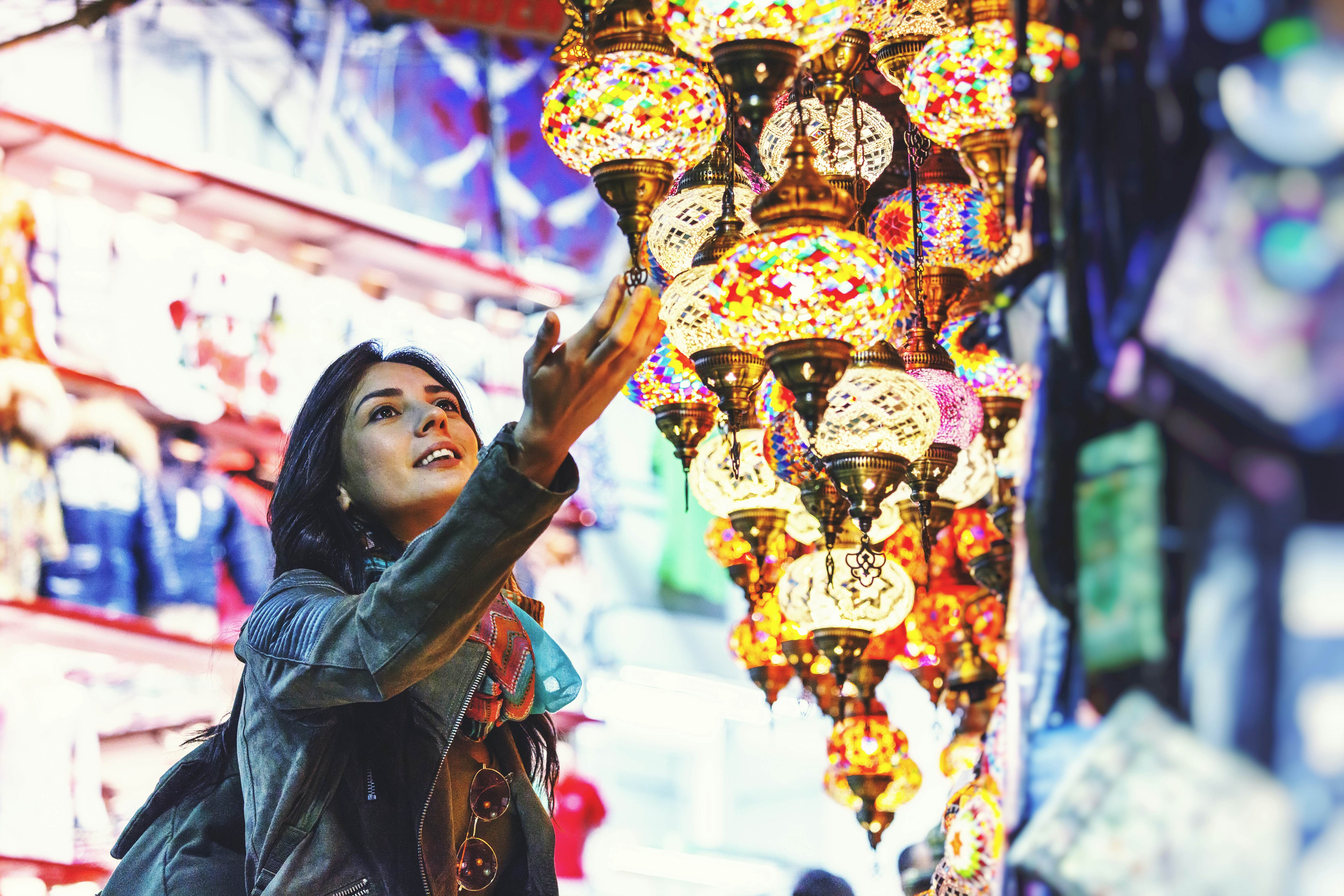 Young woman with her hand on a strand of lights in Grand Bazaar, Istanbul, Turkey 