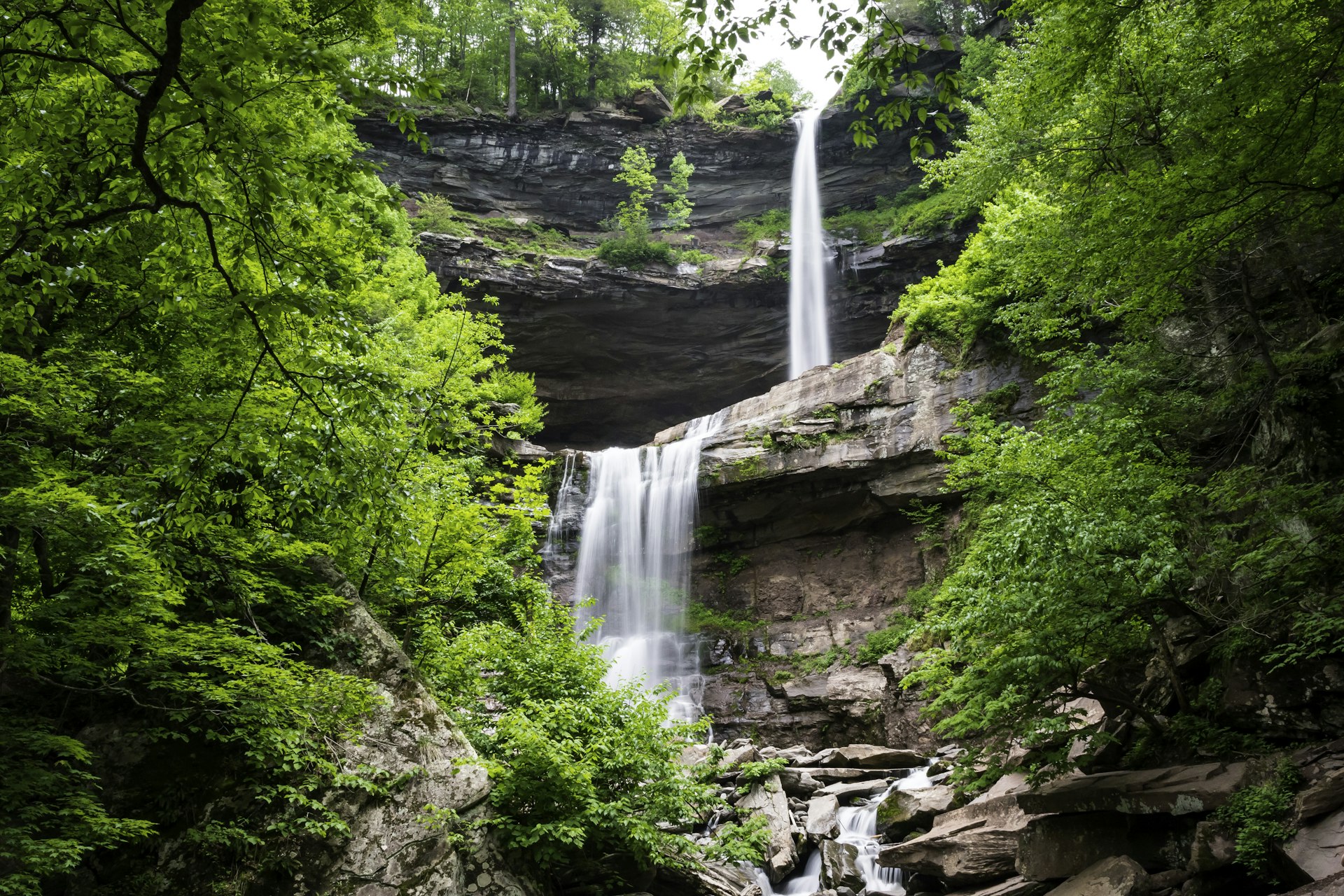 Long exposure of the two-tier Kaaterskill Falls surrounded by lush green trees during Summer