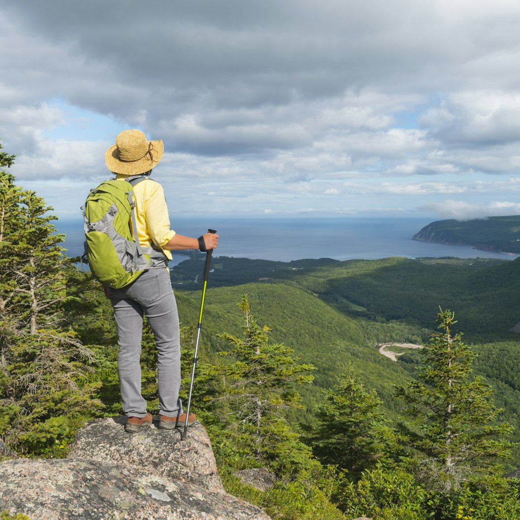 Female hiker standing at the top of a mountain in Cape Breton Highlands National Park.