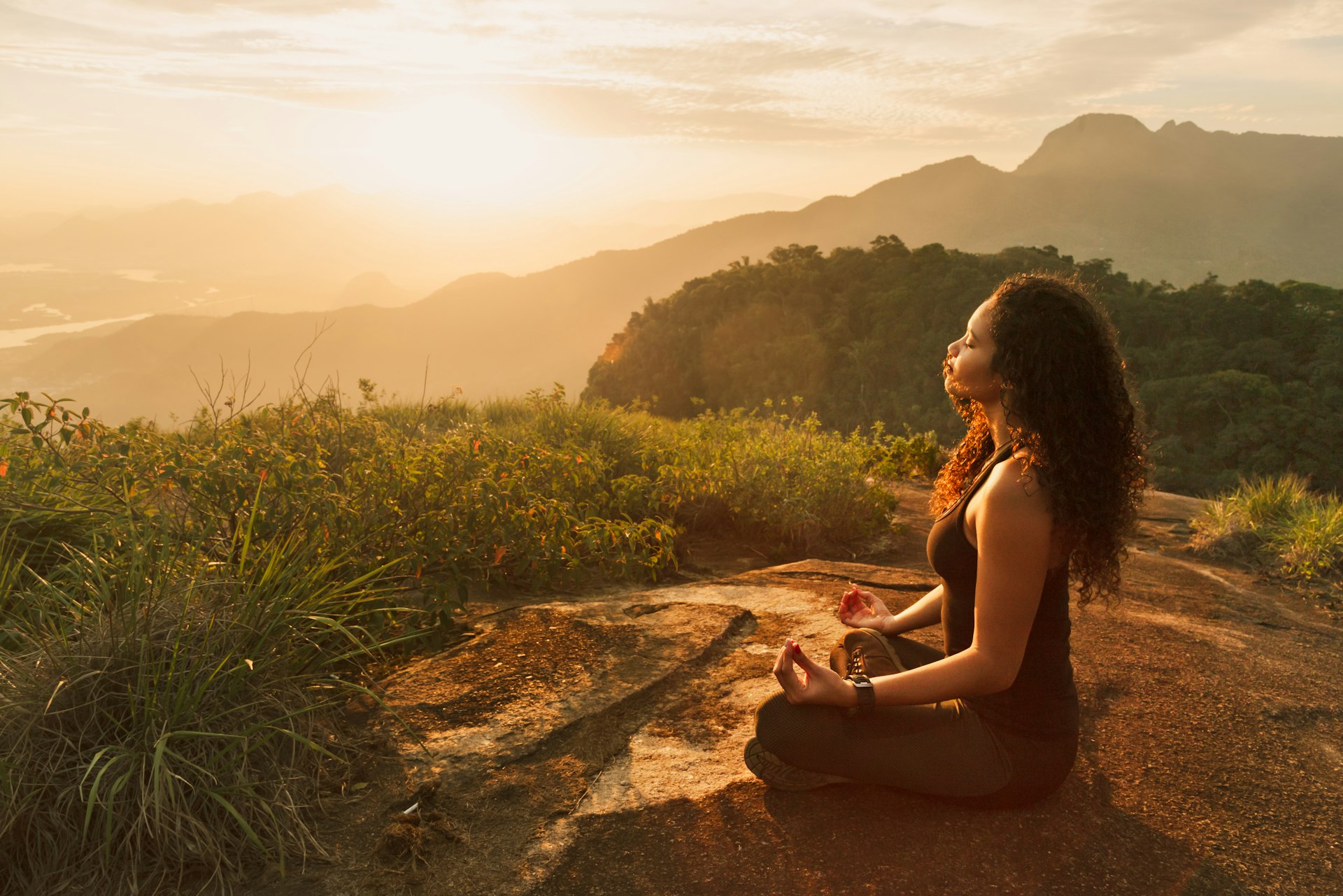 Young woman meditating on a mountain top near Rio de Janeiro